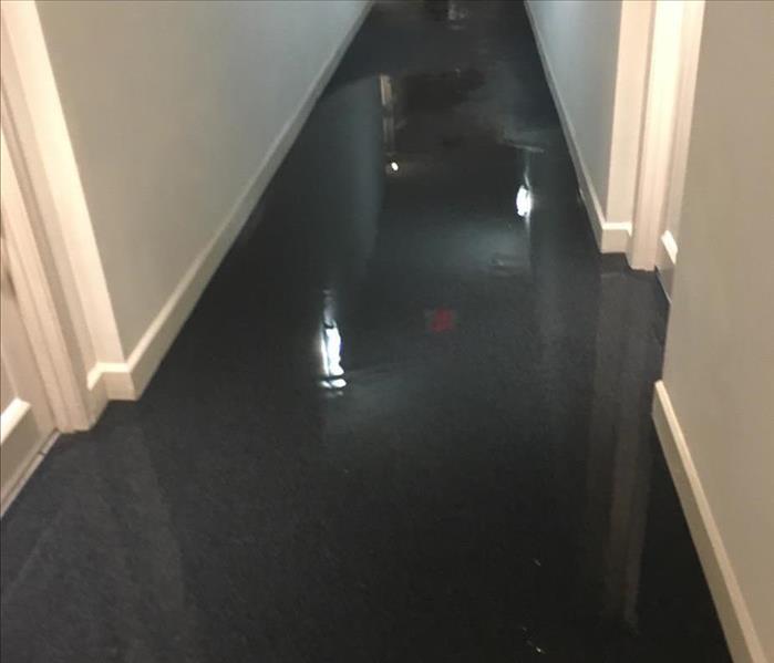 Hallway with dark floors covered in standing water. 