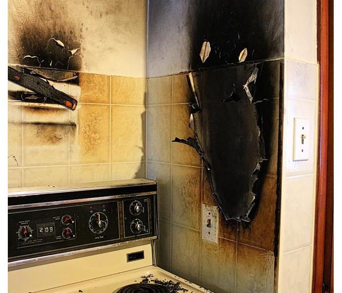 Stove top and wall burned black from a fire. 